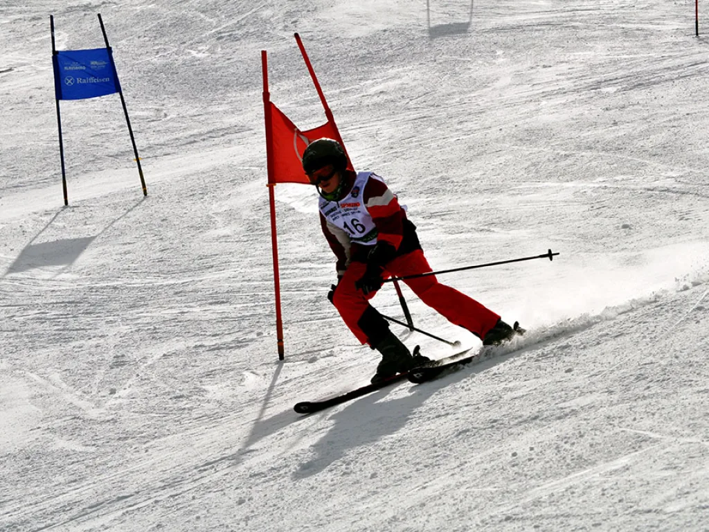 Skifahrer in roter Kleidung in der Kurve am Tor.